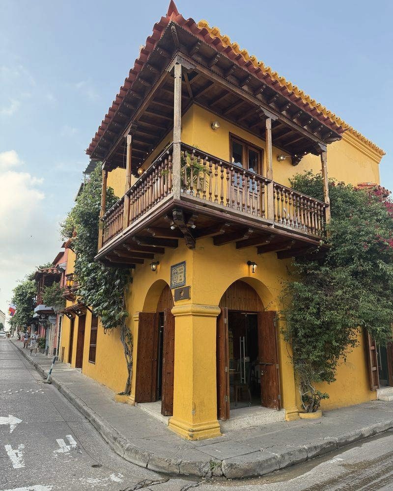 Gelbes Kolonialhaus mit Holzbalkon an einer Strassenecke